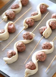 some meatballs and toothpicks are on a baking sheet