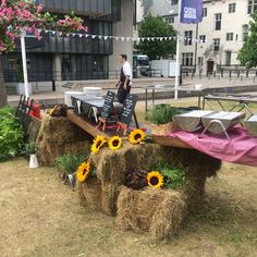 hay bales with sunflowers and signs on them in front of a building