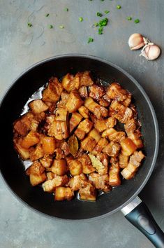 some food is cooking in a skillet on the table next to garlic and an onion