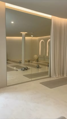 a large mirror reflecting the interior of a bathroom with white walls and floor tiles on it