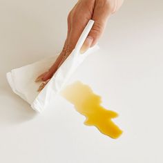 a hand holding a napkin with some food on it and yellow liquid coming out of it