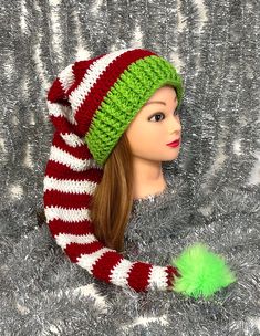 a mannequin head wearing a green and red striped knitted hat with pom - pom