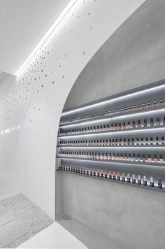 an empty room with several rows of bottles on the wall and lights in the ceiling