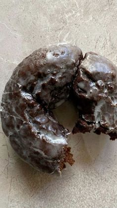 two chocolate donuts with one bite taken out