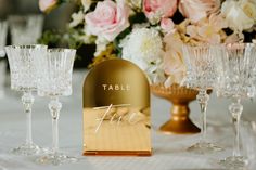 the table is set with wine glasses, champagne flutes and place cards for guests to write on