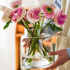 a person holding a vase with flowers in it