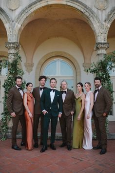 a group of people standing next to each other in front of a building with arches