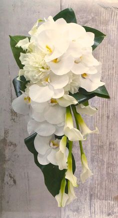 a bouquet of white flowers hanging from a wooden wall