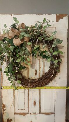 an old door with a wreath on it and a measuring tape in front of it