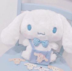 a white stuffed rabbit sitting on top of a blue chair next to cut up animals