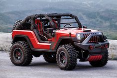 a red and black jeep parked on top of a hill