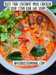 a bowl of soup with meat, vegetables and herbs in it next to a spoon