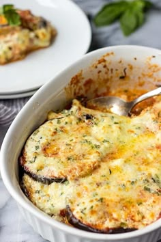 a casserole dish with cheese and vegetables in it on a table next to a plate