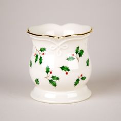 a white vase with holly and red berries on it