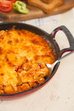 a casserole dish with cheese and meat in it on a table next to bread