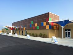 an empty street in front of a building with colorful tiles on the wall and awnings