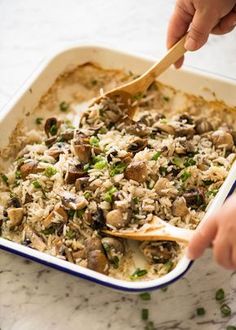 someone spooning rice into a casserole dish with mushrooms and peas on the side