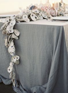 the table cloth is draped over with flowers and leaves on it, along with place settings