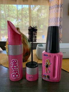 three pink and silver items sitting on top of a wooden table next to a window