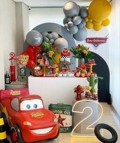 a room filled with toys and balloons in the shape of cars next to a wall