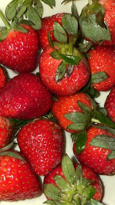 a bunch of strawberries sitting on top of a white plate next to each other