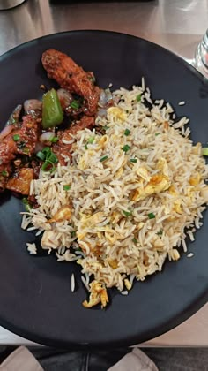 a black plate topped with rice and meat