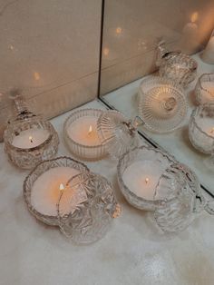 several glass dishes and candles on a counter