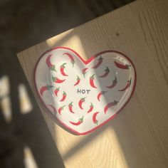 a heart shaped dish with hot peppers painted on it