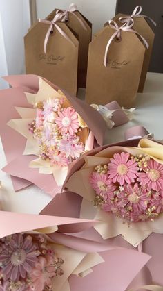 some pink flowers and brown paper bags on a table