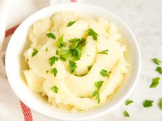 a white bowl filled with mashed potatoes and parsley