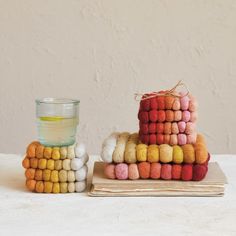 a stack of multicolored wool balls next to a glass filled with yellow liquid