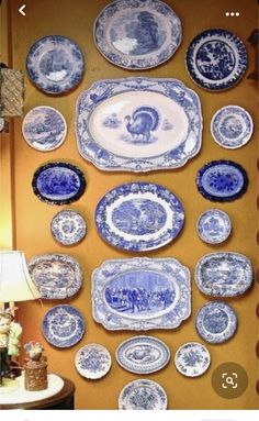 blue and white plates hanging on the wall next to a table with a lamp in front of it