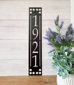 a vase filled with purple flowers sitting next to a wooden sign that says 2090