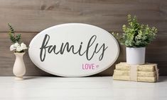 a white sign that says family on it next to some flowers and two vases