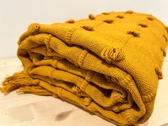 a pile of yellow blankets sitting on top of a wooden table