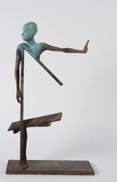 a bronze statue of a person standing on top of a wooden pole with his arms outstretched