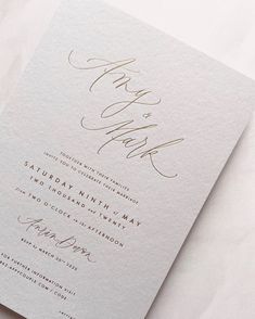 a white wedding card with gold ink on it and the word thank written in cursive writing