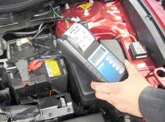 a person is working on an engine in a car with the hood open and it's battery exposed