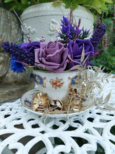 a teacup with purple flowers in it sitting on a table