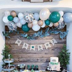 a table filled with lots of desserts and balloons on top of wooden planks