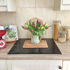 a kitchen counter with flowers in a vase on the burner and cookbook next to it