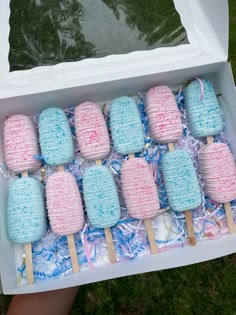 a box filled with blue and pink marshmallow pops