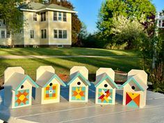 several bird houses are sitting on a table in front of a house