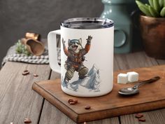 a white coffee mug with an image of a grizzly bear on it and marshmallows next to it