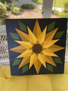 a sunflower painted on a canvas sitting on a yellow chair in front of a window