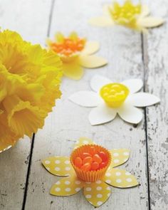 yellow and white paper flowers sitting on top of a wooden table next to each other