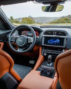 the interior of a car with brown leather seats and dashboard controls, including an automatic steering wheel