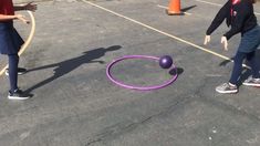 two children playing with a purple object in the parking lot