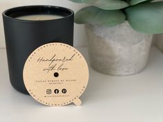 a candle next to a potted plant on a white table with a label that says handmade with love