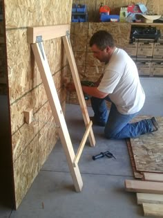 a man that is kneeling down next to a wall with some wood planks on it